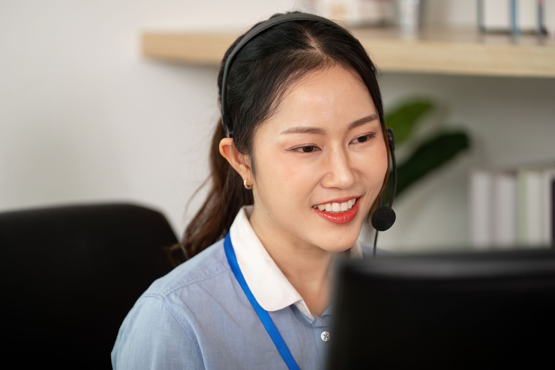 Customer Service Representative at Work. Engaged female agent smiling while assisting clients on a call.
